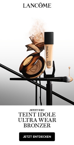 Lancôme Jetzt Neu Teint Idole Ultra Wear Bronzer - einer geöffneten Bronzer-Dose, einer Flasche Lancôme Teint Idole Flüssigfoundation und einem Make-up-Pinsel auf einem weiß-grauen Farbverlauf-Hintergrund mit einer roséfarbenen Blume im Nude-Ton.